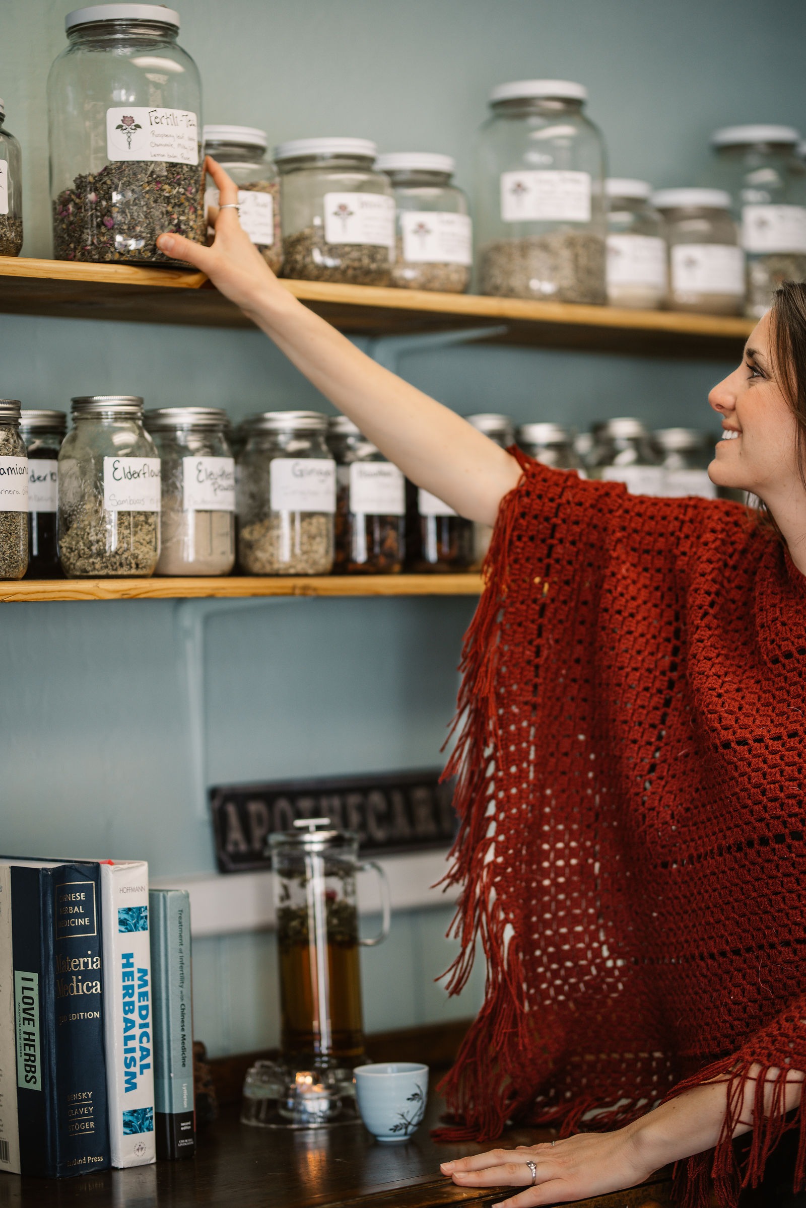 Elena reaching for herbs in the apothecary